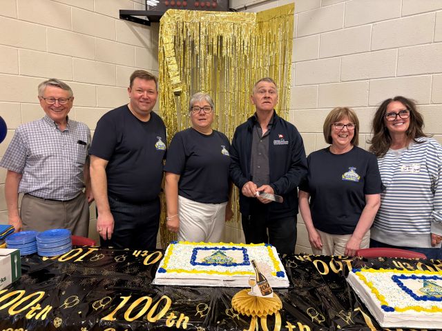 Six people cutting cake at a ceremony.