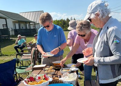 people filling plates at picnic table
