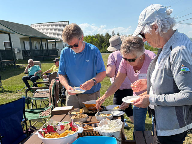 people filling plates at picnic table