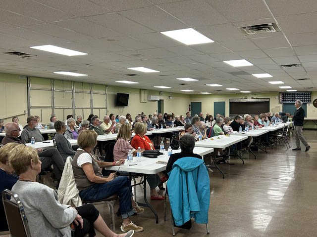 Large room full of people listening to a speaker